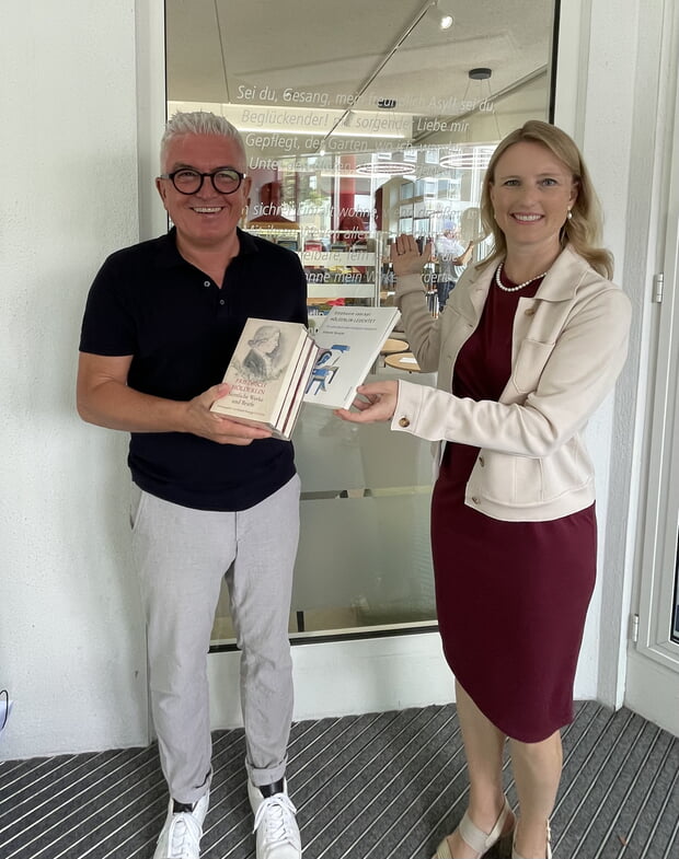 Klaus Peter Waldenberger übergibt Sarina Pfründer eine Hölderlin-Gesamtausgabe im Windfang der neuen Stadtbücherei (Foto: Christiane Waldenberger)